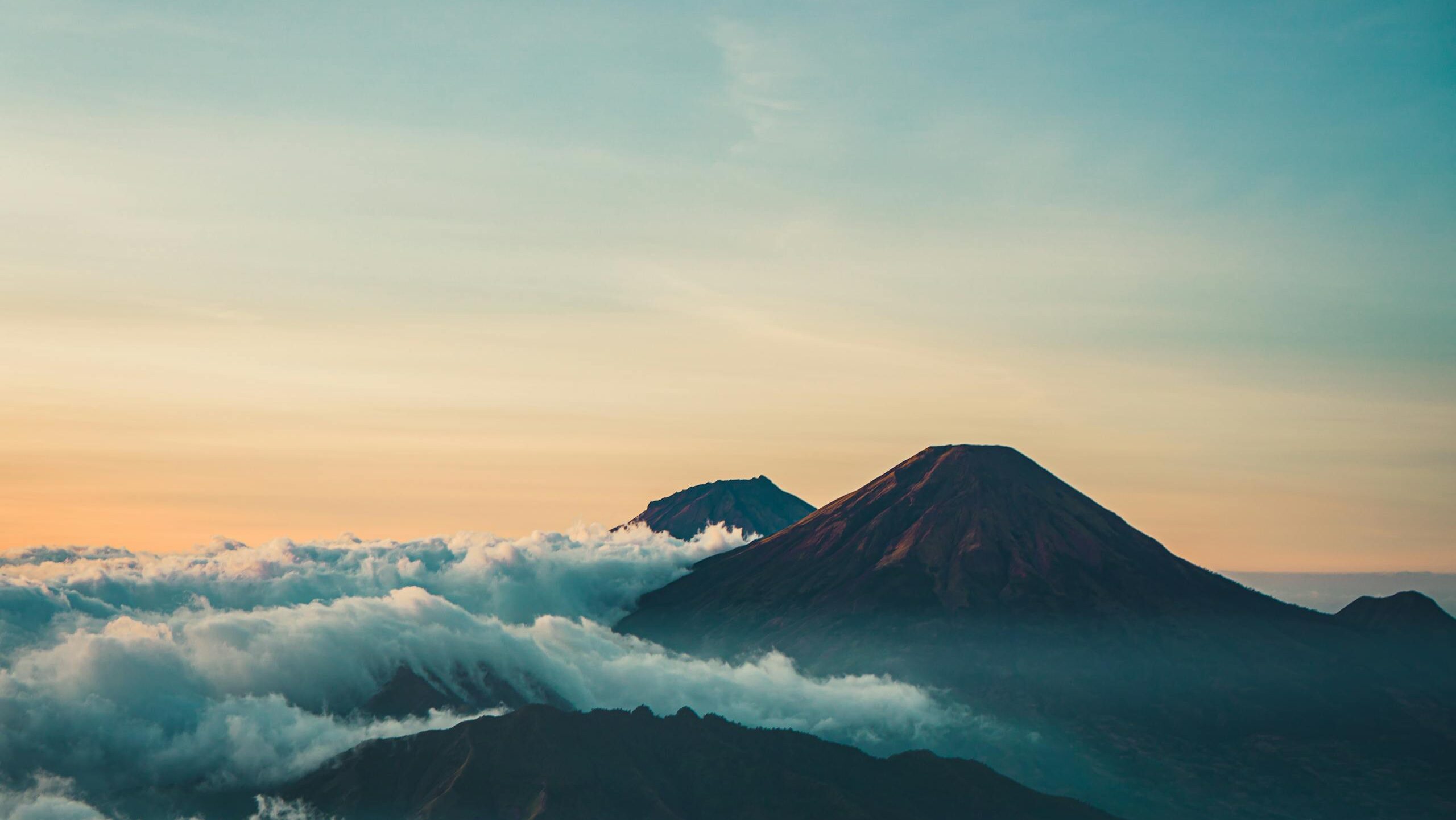 Beautiful sunrise view of Mount Sindoro with clouds and serene landscape in Java, Indonesia.